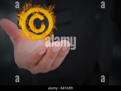 Digital composite of hand with copyrighht  fire icon over. Black background Stock Photo