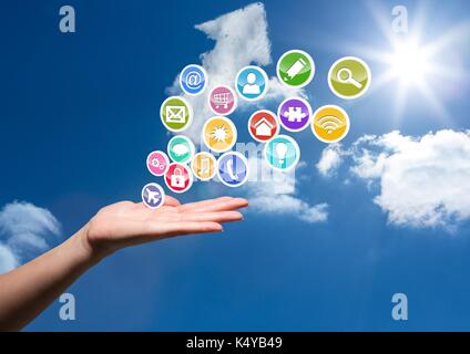 Digital composite of hand with application icons coming up form it. Sky behind Stock Photo