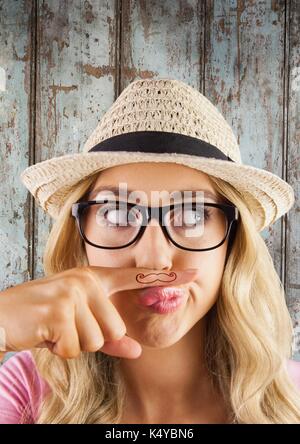 Digital composite of Millennial woman with mustache on finger against wood panel Stock Photo