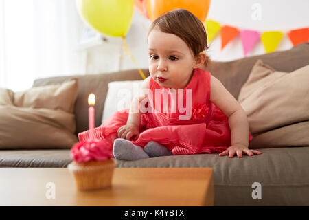 girl blowing to candle on birthday cupcake at home Stock Photo
