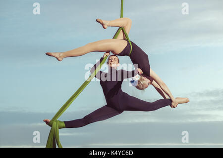 Two women aerial gymnasts perform high in the sky on hammocks. Stock Photo