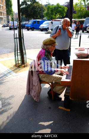 A street musician playing the piano near the antique market stalls in the Marche aux Puces, the flea market, at Porte de Vanves in Paris Stock Photo