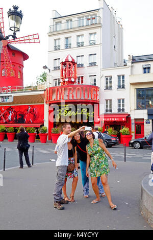 Tourists pose for a selfie group photo n front of the Moulin Rouge cabaret club in Pigalle, close to Montmartre in Paris Stock Photo