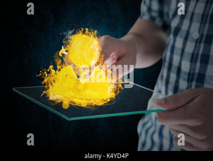 Digital composite of hands with device with contact fire icon over. Blue and black wall background Stock Photo