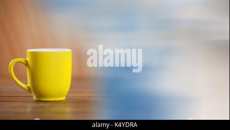 Digital composite of Yellow coffee cup with blurry sky transition Stock Photo