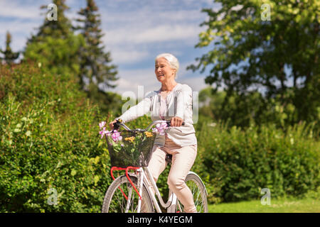 happy senior woman riding bicycle at summer park Stock Photo