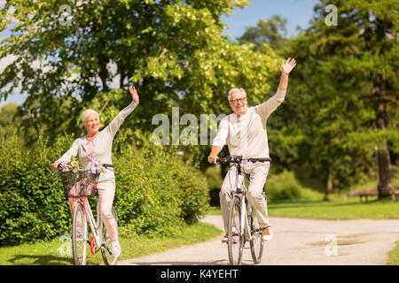 happy senior couple riding bicycles at park Stock Photo