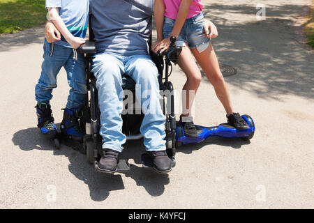 Disabled father on the wheelchair playing with children. Stock Photo