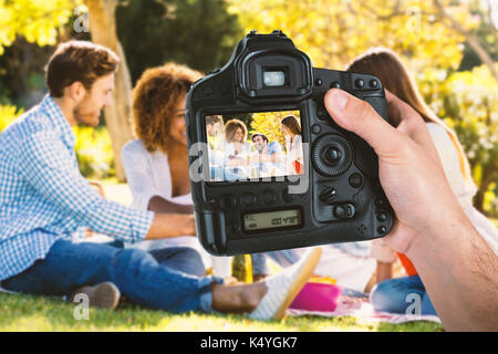 Cropped hand of photographer holding camera  against friends toasting glasses of wine while having breakfast Stock Photo