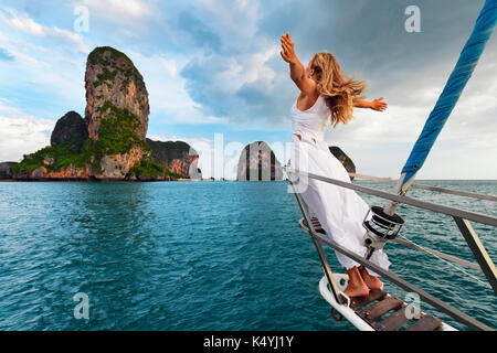 Joyful young woman portrait. Happy girl stand on deck of sailing yacht, have fun discovering islands in tropical sea on summer coastal cruise. Travel 