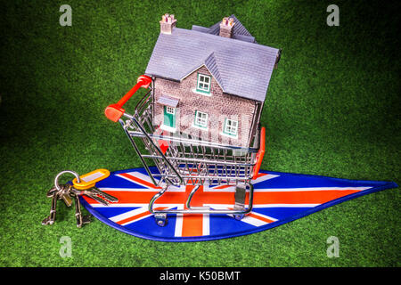 Model house in a model shopping trolley, with house keys, on Union Jack colours. A concept to depict the UK housing market of home buying or renting. Stock Photo