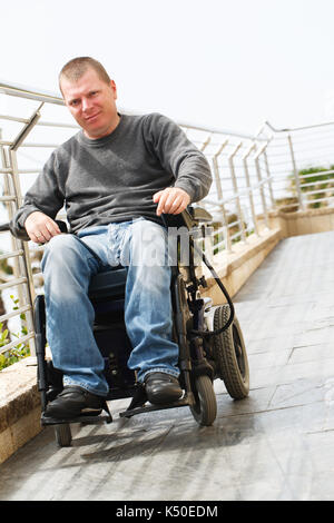 Man in wheelchair sits near the railing Stock Photo