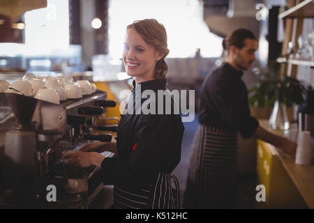 Side view of smiling young baristas working at coffee shop Stock Photo