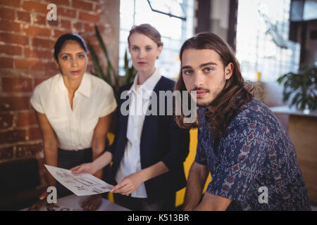 Portrait of confident young creative team standing with documents at coffee shop Stock Photo
