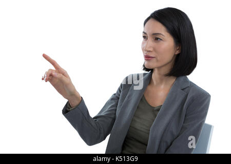 Businesswoman touching invisible screen against white background Stock Photo