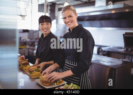 Portrait of smiling female chefs preparing food in kitchen at coffee shop Stock Photo