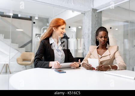 Two attractive businesswomen using technology