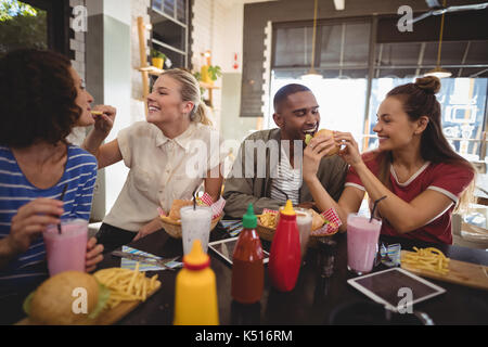 Young friends sharing food at table in coffee shop Stock Photo