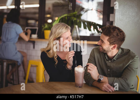 Smiling young couple with fresh dessert while sitting at table in coffee shop Stock Photo