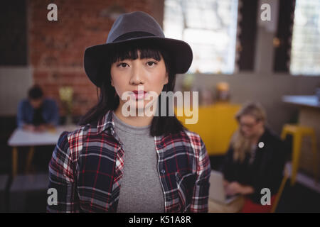 Portrait of confident young woman wearing hat while standing at coffee shop