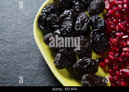 Close-up of dates fruits with pomegranate seeds in plate on slate Stock Photo