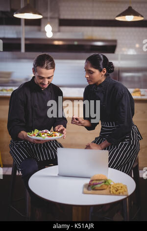 Young wait staff discussing over food while sitting at table in coffee shop Stock Photo