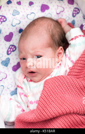 Newborn baby awaken in the crib, looking at the camera with her eyes wide open Stock Photo