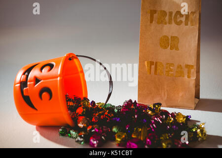 Trick or treat text on paper bag by bucket and colorful chocolates on white background Stock Photo