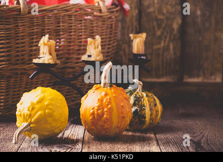 Autumn cozy home decorations. Still life with wicker basket, candles, mini pumpkins and red-checked napkin in rustic style Stock Photo