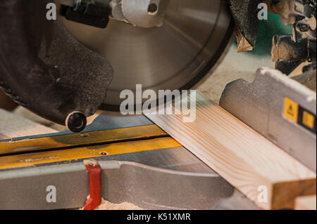 Circular saw with a wooden beam and measuring scale. Sawing a wooden beam with a circular saw. in progress Stock Photo