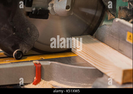 Circular saw with a wooden beam and measuring scale. Sawing a wooden beam with a circular saw. abother view close up Stock Photo