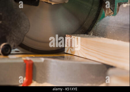 Circular saw with a wooden beam and measuring scale. Sawing a wooden beam with a circular saw. in progress view Stock Photo