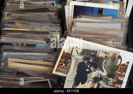 ATHENS, GREECE - MAY 21, 2015: Old photos and vintage postcard prints for sale at flea market. Young couple romancing on swing decorated with flowers. Stock Photo