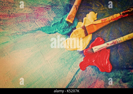 Brushes and colors on painted canvas Stock Photo