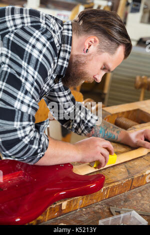 Craftsman sanding a guitar neck in wood at workshop Stock Photo