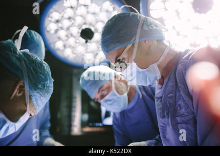 Concentrated female surgeon performing surgery with her team in hospital operating room. Medics during surgery in operation theater. Stock Photo
