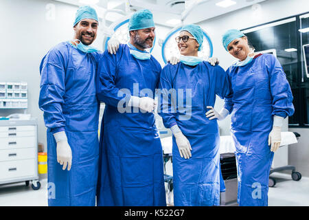 Portrait of successful surgeon team standing in operating room. happy medical workers in surgical uniforms in operation theater. Stock Photo