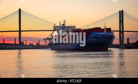 A commercial cargo ship as it leaves the Port of Savannah in Georgia at sunset Stock Photo