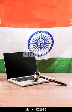 india and cyber law, laptop and wooden gavel or hammer placed over wooden table and indian tricolour or flag in the background showing cyber law in In Stock Photo