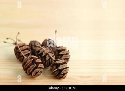 Closed up many natural dry tiny pine cones on light brown wooden table, with free space for text design Stock Photo