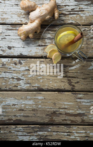 Overhead view of cinnamon and lemon in ginger tea on weathered wooden table Stock Photo