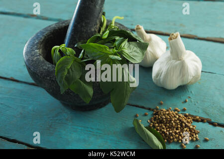 Close-up of mortar and pestle with herbs and spices on wooden table Stock Photo