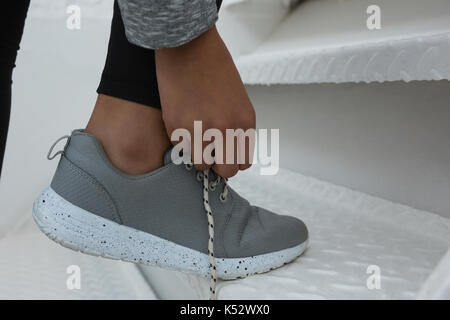 Low section of female athlete tying shoelace on stairs Stock Photo