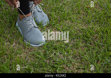 Low section of female athlete tying shoelace on field Stock Photo