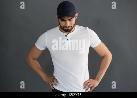 Handsome man posing with hand on hip against grey background Stock Photo