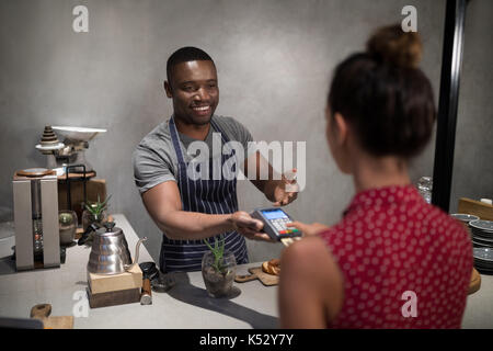 Customer making payment through credit card at counter in cafe Stock Photo