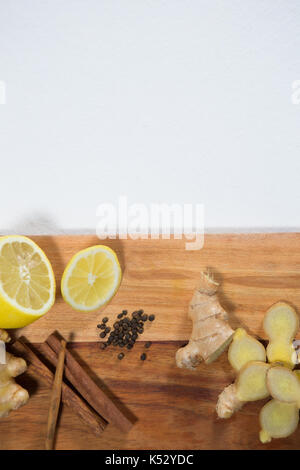 Overhead view of lemon and various spices on wooden serving board against white background Stock Photo