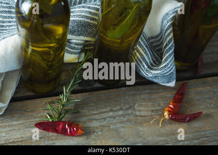 Olive oil bottles with herbal and spices on wooden background Stock Photo