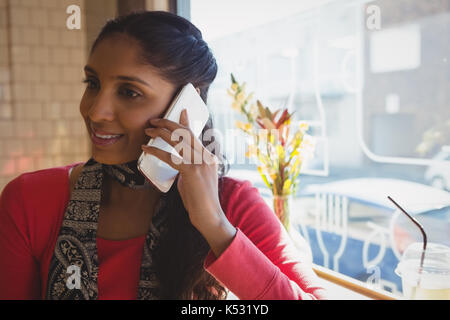 Young woman looking away while talking on mobile phone in cafe Stock Photo