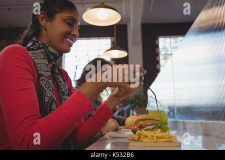 Young woman photographing French fries at counter in cafe Stock Photo